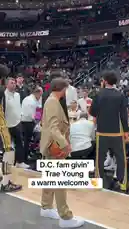 In a heartwarming moment before a game, Trae Young is greeted by Washington Wizards fans and players on the court. Dressed sharply in a tan suit, he waves enthusiastically to the crowd, holding a basketball as he walks through the tunnel area. This friendly reception highlights the positive connection between the star player and his fanbase. by @washwizards with original sound