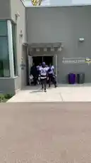 This video shows Minnesota Vikings football players walking out of the TCF Bank Stadium Training Center. They are wearing their white practice jerseys with purple numbers and black shorts, carrying their helmets. One player, wearing jersey number 44, walks towards the camera before turning away. The scene captures a moment during a team practice session. by @vikings with original sound