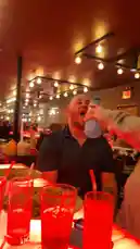 dassweenbean 님이 만든 Original Sound 포함 @dassweenbean 님이 만든 A man sits at a table in a dimly lit restaurant while another person holds a water bottle to his mouth. The man drinks from the bottle before turning to smile at the person holding it.