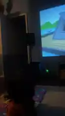 A young child sits on a colorful alphabet mat in a dimly lit living room, captivated by a classic Looney Tunes cartoon playing on a large projector screen. The animated scene features Sylvester the Cat on a boat, attempting to catch Tweety Bird, while the toddler watches intently. The cozy, homey atmosphere highlights a simple, joyful moment of a child enjoying timeless animation. by @marcus.randall with Original Sound by marcus.randall