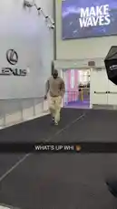 A player associated with the LA Clippers walks through a modern building entrance into a branded event space featuring prominent 'Lexus' and 'MAKE WAVES' signage. He casually approaches a glass door while being filmed, suggesting a media appearance or promotional activity. by @clippers with Original Sound by clippers