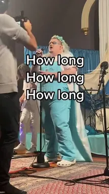 Watch as artist TALK performs live on stage, announcing their debut EP release date of Friday, November 19th. The performer, dressed in light blue overalls and a white shirt, sings into a microphone while a guitarist plays in the background. In a direct address to the audience, they share their excitement about being a new artist and encourage fans to check out their music on Spotify. by @iamtalk with iamtalk by Original Sound