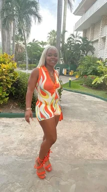 오리지널 사운드 포함 @brattyluhbaby 님이 만든 In this stylish outdoor scene, Baby 💫 confidently poses in a vibrant orange flame-patterned romper and matching high-heeled sandals. Set against a tropical backdrop with palm trees and lush greenery, she showcases a bold summer look perfect for vacation or a fashion-forward outing.