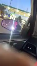 오리지널 사운드 포함 @abdoufall205962 님이 만든 This first-person perspective captures a moment inside a car at a gas station during twilight. The camera focuses on the side mirror, reflecting the colorful lights of the station and the darkening sky. The dashboard controls and the view through the windshield provide context for a routine stop.