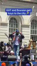 Kyrie Irving and Jalen Brunson are honored with keys to New York City during a celebratory parade event. Both players are seen shaking hands and hugging a city official on stage, with multiple NBA Championship trophies visible behind them. The crowd cheers as the athletes celebrate their team's success. by @yahoosports with Original Sound by yahoosports