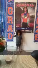 This video captures a family celebrating a graduation milestone at home. It begins with a young child standing proudly in front of 'GRAD' banners and a poster for Christian Randall, a hurdlr from the Class of 2026 at Hanahan High School. The scene then transitions to a cozy living room where adults relax on a couch, watching TV and using their phones, while children play nearby. The overall atmosphere is one of casual celebration and family bonding. by @marcus.randall with Original Sound by marcus.randall