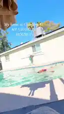 A serene backyard pool scene unfolds under a clear blue sky. A person enjoys swimming in the inviting turquoise water, their movements creating gentle ripples. In the background, a house with an air conditioning unit and palm trees adds to the tranquil, sunny-day atmosphere. by @seriouslyfd with Original Sound by seriouslyfd