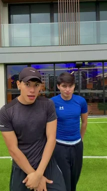 In this energetic clip, S E B A S 🧸 performs a series of cool dance moves and hand gestures on a green artificial turf field. He is joined by a friend, and they interact playfully, showcasing their coordination and fun personalities against the backdrop of a modern building. by @twinksebass with Original Sound by Contains: Me Estas Tentando - Wisin & Yandel