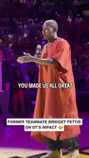 A heartfelt tribute unfolds on a basketball court as a coach is celebrated by fans and players alike. The speaker, dressed in a striking orange robe, delivers an emotional speech acknowledging the collective greatness achieved under her leadership. The crowd's roar of approval fills the arena, capturing a moment of unity and appreciation in women's professional sports. by @wnba with Original Sound by wnba