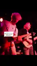 Witness an energetic live music performance by a dynamic duo of guitarists on stage. The musicians, bathed in vibrant red and purple stage lights, deliver an electrifying show. One guitarist, wearing a white shirt and light-colored pants, plays a dark electric guitar, while his bandmate, in a black jacket and jeans, strums a light-colored electric guitar. Their passionate playing and stage presence create an immersive concert experience. by @iamtalk with iamtalk by Original Sound