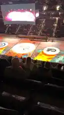 In a vibrant arena filled with fans, mascot Gritty of the Philadelphia Flyers takes center stage on the ice rink. Dressed in his signature orange jersey and black helmet, he skates energetically, performing playful moves and waving to the crowd. The camera captures dynamic angles of his performance under the bright lights, showcasing the lively atmosphere of the event. by @squashha with squashha by Original Sound