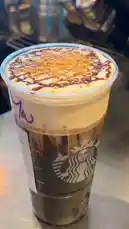 A close-up shot of a Starbucks Salted Caramel Mocha Frappuccino, showcasing its creamy texture, whipped cream topping, caramel drizzle, and crumbled cookie garnish. The cup features the iconic Starbucks logo and a handwritten 'M' on the sleeve. This visually appealing beverage is presented as part of a review or recipe demonstration. by @mts550 with original sound