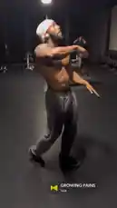 A shirtless man, identified as Cole, performs a dynamic workout in a dimly lit gym. He flexes his muscular physique while moving rhythmically, showcasing his fitness dedication. The energetic atmosphere and physical exertion highlight a moment of personal growth and strength training. by @jcoleworld00 with GROWING PAINS by Yeat