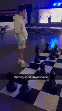 Witness an epic life-size chess match unfold in a vibrant event space. Two players engage in a strategic battle, maneuvering giant black and white pieces across a massive checkered floor. The atmosphere is electric with onlookers and event branding visible in the background, capturing the excitement of competitive chess. by @chesscom with Original Sound by chesscom