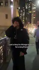 In this nighttime scene, Evan walks along a bridge in Chicago, with the city's illuminated skyline and river in the background. The text overlay reads 'just a boy in chicago looking for a boyfriend,' setting a personal and urban tone. by @evanjakeof with Original Sound by evanjakeof