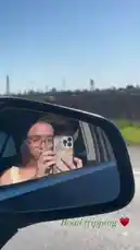 A behind-the-scenes glimpse into Ruby Jay's road trip, captured through her car's side mirror. She takes a selfie with her phone while driving, showcasing her style and the scenic journey. by @iamrubyjay with original sound
