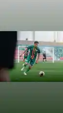 A dynamic scene from a football training session featuring a player from Al-Rawdah Club. Dressed in a green jersey with orange accents, the athlete skillfully controls the ball on a well-maintained pitch. The background reveals teammates and a goalpost, capturing the essence of professional club practice. This authentic glimpse into Saudi football culture highlights athletic precision and team coordination. by @alrawdahclub with original sound