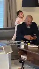 A man sits on a couch, completely focused on his phone. A toddler in pink pajamas stands behind him, holding a small brush. She playfully pretends to do his hair, mimicking a job, while also poking her head into his personal space. The man's exaggeratedly annoyed expression perfectly captures the relatable struggle of parenting, all set to a dramatic soundtrack. by @christamic3 with Original Sound by christamic3
