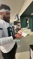 In this fun locker room moment, Philadelphia Eagles players gather around a novelty 'Mini Prints' machine. They take turns inserting coins and receiving small paper prints, reacting with surprise and amusement to their random results. One player gets a print of a pretzel, another a cheesesteak, and a third one gets a print of the phrase 'Go Birds!' The players joke about the prints, with one even getting a fortune cookie-style message saying 'You will meet a great friend one day.' It's a lighthearted look at team bonding and the simple joys of trying something new. by @eagles with Original Sound by eagles