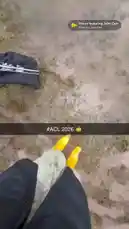 This point-of-view clip captures a fun day outdoors in the mud. It starts with a close-up of a black dog drinking from a puddle, then pans up to show a person in yellow rain boots walking through the muddy field. The scene shifts to a smiling woman in a camouflage hat and dark jacket, who playfully points at her teeth before turning the camera to reveal a large crowd and a body of water in the background, suggesting a festival or park event. by @snapcreators with House featuring John Cale by Charli xcx, John Cale