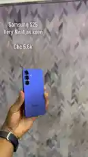 A hand holds a blue Samsung Galaxy S25, showcasing its design before navigating through the phone's settings menu. On-screen text indicates the device is 'Very Neat as seen' and priced at 'Ghc 5.6k'. by @ab_god18 with Original Sound by ab_god18