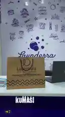 A behind-the-scenes look at the Launderra laundry service's branding setup. The camera pans across a branded paper bag, a laptop, and a promotional standee, all featuring the company's logo and name. This glimpse into the business's front-end presentation showcases its modern aesthetic and professional materials. by @launderra with Original Sound by launderra