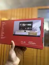 A close-up, hands-on unboxing of a sleek red Android TV box by Frekas Global. The packaging highlights features like 'Powered by androidtv' and displays a modern living room setup on the front, enticing viewers with its smart TV capabilities. This visual guide reveals the product's design and promises a seamless streaming experience. by @frekasglobal with original sound