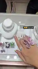 A close-up view of a hand modeling a large, sparkling butterfly-shaped ring, with other diamond jewelry displayed in the background. by @moneeragh with Original Sound by moneeragh