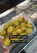 A close-up view of fresh green olives stuffed with red peppers, displayed in a clear plastic container. Text overlay shows the price as 19.99 Riyals, suggesting a retail setting like a grocery store or deli counter. The presentation highlights quality and freshness, appealing to customers looking for ready-to-eat snacks or meal ingredients. by @hyperalwafa with original sound