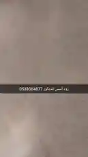 This video showcases various wall textures and design elements from Zood Asas Decoration. It begins with close-up shots of different wall finishes, including a smooth surface and a textured 'stucco' style wall. A hand points out specific features, highlighting the material's quality. The camera then pans across a modern interior space, revealing a large decorative wooden screen with intricate carvings, a contemporary dining table, and stylish chairs. The setting appears to be a well-lit room with a view of an outdoor area through a window or balcony, emphasizing the blend of traditional craftsmanship with modern design aesthetics. by @zoodasas with Original Sound by zoodasas
