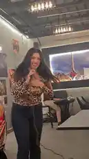 A woman sings into a microphone while standing in a room with tables and chairs. She wears a leopard print top and jeans. A man sits at a keyboard playing music for her. The camera moves around her as she performs. by @mo.fouadziko with Original Sound by mo.fouadziko