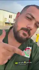 A close-up selfie shows a man in an Egyptian Air Force uniform proudly pointing to a new 'Zero Harm Environmental' patch on his olive green flight jacket. He is outdoors in a sunny, arid environment near temporary buildings. The scene captures a moment of military pride and environmental awareness. by @vii35_1 with Original Sound by vii35_1