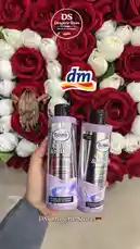 A hand holds two bottles of Balea Glow & Shine shampoo and conditioner against a luxurious backdrop of red and white roses. The DS Drogerie Store logo is visible, indicating a promotional display for the German beauty brand. by @dsdrogeriestore with ‌✨ by Contains: Hasrat - Morteza Pashaei