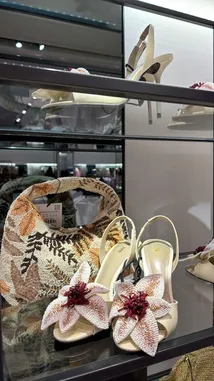 A close-up showcase of luxury women's accessories, featuring intricately beaded floral heels and a matching embroidered handbag. The display highlights detailed craftsmanship and modern fashion design, set within a stylish retail environment. by @ru.ab71 with original sound