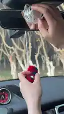A person demonstrates how to hang a handmade, crocheted Spider-Man figure inside a car using a string attached to the rearview mirror. The red and blue character sways gently, showcasing a creative and fun way to personalize your vehicle. by @r200an with Original Sound by r200an