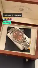 A close-up view of a luxurious West End Watch Co. timepiece displayed in its elegant presentation box. The watch features a distinctive reddish-brown dial with Arabic numerals and a stainless steel bracelet. On-screen text highlights the price as '3500' and includes the brand name 'tamara'. This unboxing-style clip is ideal for collectors and enthusiasts interested in Swiss watches and luxury accessories. by @lussowatches with original sound