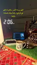 A serene morning scene from Merchat Noor's personal space, showcasing a cozy study setup with a laptop, coffee, and tea. The Arabic text overlay reads 'The morning is for the dawn, and the night is for sleep,' setting a peaceful tone. This tranquil environment highlights a balanced lifestyle focused on productivity and self-care. by @ghs-rhf with original sound