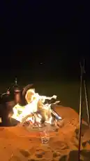 A serene night scene at a desert campsite, featuring a crackling fire built in the sand. Beside it sits a traditional Arabic coffee pot, known as a dallah, glowing in the warm light. A voiceover recites a poetic message about boundaries and respect, creating a contemplative atmosphere. This moment captures the essence of hospitality and tradition, presented by سوليدير للمناسبات و الضيافة ✪. by @soldere.ledyafa with Original Sound by soldere.ledyafa