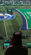 Experience the grandeur of the FIFA World Cup 2022 opening ceremony from a unique perspective. This high-angle view captures the Saudi Arabian national team lined up on the pitch, with the iconic Saudi flag prominently displayed. In the foreground, a man wearing a traditional ghutra observes the event, symbolizing national pride. The stadium is filled with fans, creating an electric atmosphere for the world's biggest football tournament. by @abood114 with Original Sound by abood114