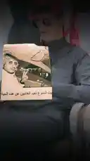 يظهر هذا المشهد حسين المنهالي وهو يجلس في بيئة داخلية، يرتدي ملابس تقليدية سعودية ونظارات شمسية، ويحمل ورقة عليها صورة رجل بزي عسكري تقليدي. تشير النصوص العربية المرئية على الورقة إلى 'النوم عن الغانين' و'هذه الحياة'. المشهد يوحي بأن المنهالي يقدم محتوى تحليلي أو إخباري حول شخصيات سياسية أو عائلات حاكمة، مع التركيز على التفاصيل الخفية أو غير المعروفة. تُستخدم الإضاءة الخافتة والتركيز على الورقة لخلق جو من الجدية والغموض، مما يشجع المشاهدين على متابعة المحتوى للحصول على المزيد من المعلومات. by @hussain.2022a with uo.n21 by Original Sound
