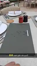 This close-up shot captures the unboxing of a sophisticated menu from ALEMAR CONCEPT. The camera focuses on a hand opening a dark green folder to reveal a neatly printed menu with elegant typography. The setting appears to be a modern restaurant table, complete with plates, cutlery, and condiments, creating an atmosphere of refined dining. This moment highlights the attention to detail and premium experience offered by ALEMAR CONCEPT. by @alemarconcept with original sound