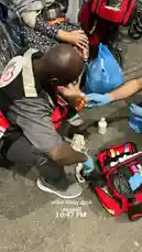 In a powerful display of community service, the فريق رسالة سلام التطوعي volunteer team administers immediate first aid to an injured individual. A responder, wearing a gray uniform and gloves, carefully treats a foot wound while another person holds the patient's leg steady. The red medical bag is open, revealing essential supplies like gauze and antiseptic. The timestamp shows the event occurred at 10:47 PM. This real-time emergency care highlights the critical role of trained volunteers in crisis situations. by @peace.message with original sound