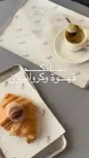 This video captures a serene morning coffee moment. It opens with a beautifully styled flat lay of a croissant topped with a pecan and cream, served on branded Sequence Coffee paper. Next to it sits a small espresso cup with a spoon, ready to stir, and a glass of water on a matching tray. The scene is calm and inviting, showcasing a simple yet elegant café experience. Arabic text overlays 'مُسَائِكُمْ قهوة و كرواسون' (Good morning, coffee and croissant), enhancing the welcoming theme. This visual is ideal for anyone searching for coffee shop aesthetics, morning inspiration, or branding ideas. by @sequence-coffee with original sound