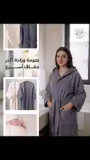 This visually appealing video showcases RJ's new robe line, emphasizing soft textures, stylish designs, and versatile colors like grey and cream. A model confidently displays the comfortable, hooded robes in a serene bathroom setting, highlighting details such as spacious pockets and adjustable belts. The Arabic text 'نعومة وراحة أكثر' translates to 'More softness and comfort,' reinforcing the product's core benefits. by @rjrobes with original sound