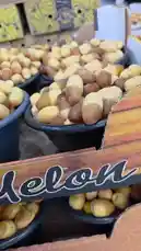 This video provides a close-up tour of a vibrant market stall overflowing with fresh dates. The camera pans across numerous black plastic buckets filled with golden and amber-colored dates, showcasing their abundance and variety. In the background, other produce like vegetables can be seen, establishing the setting as a bustling local market. The audio features a person speaking in Arabic, adding to the authentic atmosphere of the location. by @qvalleys with Original Sound by qvalleys