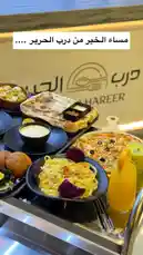 A beautifully arranged buffet spread at Al Hareer Restaurant, featuring a variety of dishes including pizza, pasta with colorful vegetables, grilled flatbread, dips, and fresh fruit. The modern presentation highlights the restaurant's diverse menu offerings. by @darbalhareer with original sound