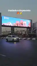 This dynamic footage captures a large-scale digital billboard campaign by Ouda Developments, showcasing their brand identity and partnership with Bravo. The ad transitions through various visuals, including architectural renderings and event scenes, all displayed prominently above a busy urban road. This real-world example highlights modern outdoor advertising strategies and brand visibility techniques. by @ouda_dev with Original Sound by ouda_dev