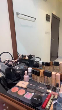 A behind-the-scenes look at آرتستَ روآبي's meticulously organized makeup vanity. The camera pans across a wide array of professional-grade products from brands like MAC, Huda Beauty, and NARS, showcasing her extensive collection of foundations, powders, brushes, and palettes. This glimpse into her workspace highlights the tools of her trade for creating flawless beauty looks. by @rii.38 with original sound