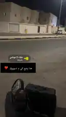 A nighttime street view shows black luggage placed on the pavement. In the background, a white building with arched windows is visible under artificial lighting. An audio track plays, featuring a person crying and sobbing intensely, creating a somber and emotional atmosphere. by @rii.38 with بكاء لا نهائي by Shosh