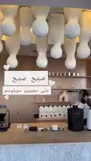 A stylish interior view of Sequence Coffee, showcasing modern design elements like unique pendant lighting and a clean counter setup. Arabic text overlays provide context, while ambient music plays in the background. by @sequence-coffee with صباح فيروز ❤️❤️ by Contains: يا انا وياك - فيروز